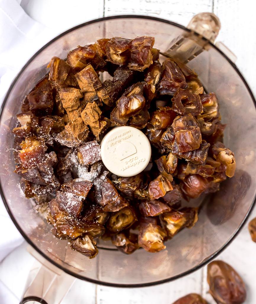 over head photo of food processor filled with dates, salt and cinnamon