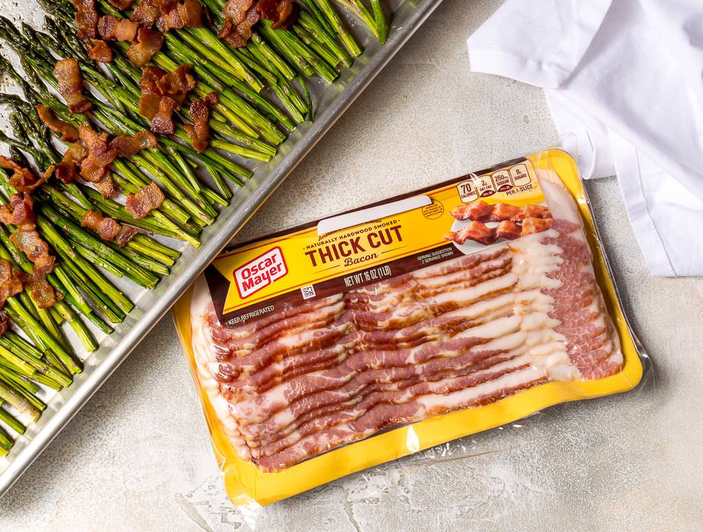 oscar mayer thick cut bacon package next to sheet pan with asparagus and bacon