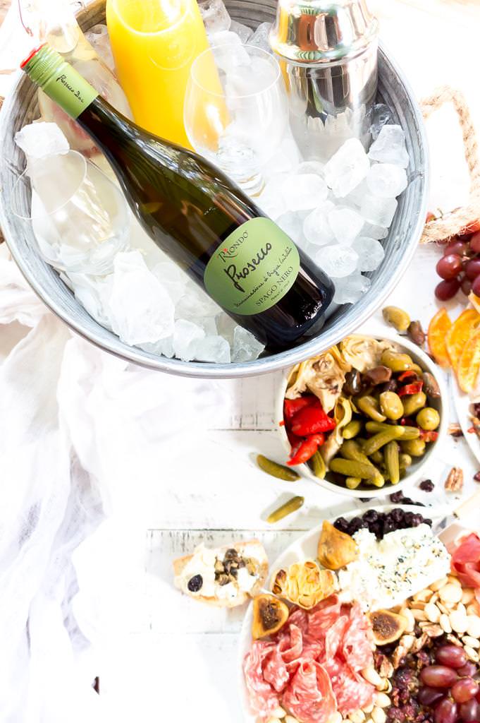 Throw an EPIC Summer Party without even turning your oven on! This Charcuterie Board and Orange 75 Cocktails are perfect for entertaining. The cheese platter is is loaded with meats, cheeses, crackers, fruits, nuts and more. And this simple cocktail recipe is sure to impress your guests! #entertaining #partyideas #cheeseboard #cocktailrecipes