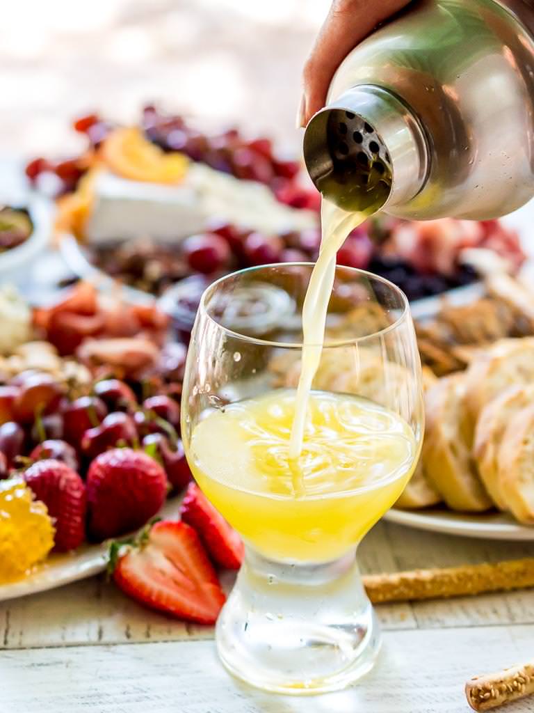 Throw an EPIC Summer Party without even turning your oven on! This Charcuterie Board and Orange 75 Cocktails are perfect for entertaining. The cheese platter is is loaded with meats, cheeses, crackers, fruits, nuts and more. And this simple cocktail recipe is sure to impress your guests! #entertaining #partyideas #cheeseboard #cocktailrecipes