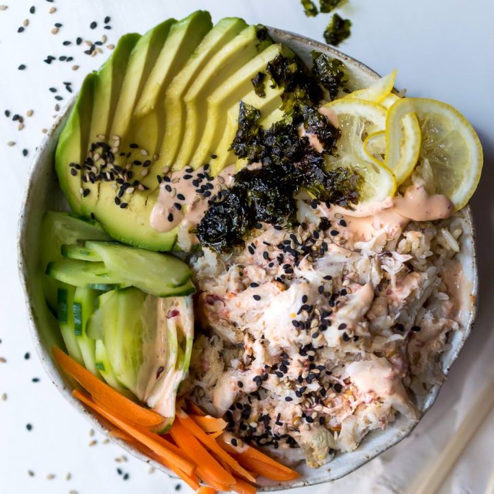 over head photo of sushi bowl filled with avocado, cucumber, carrots, lemon, crab and seaweed