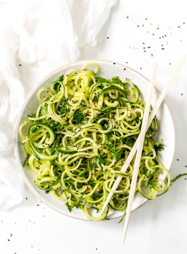 Asian cucumber salad recipe in a white bowl with chopsticks on top