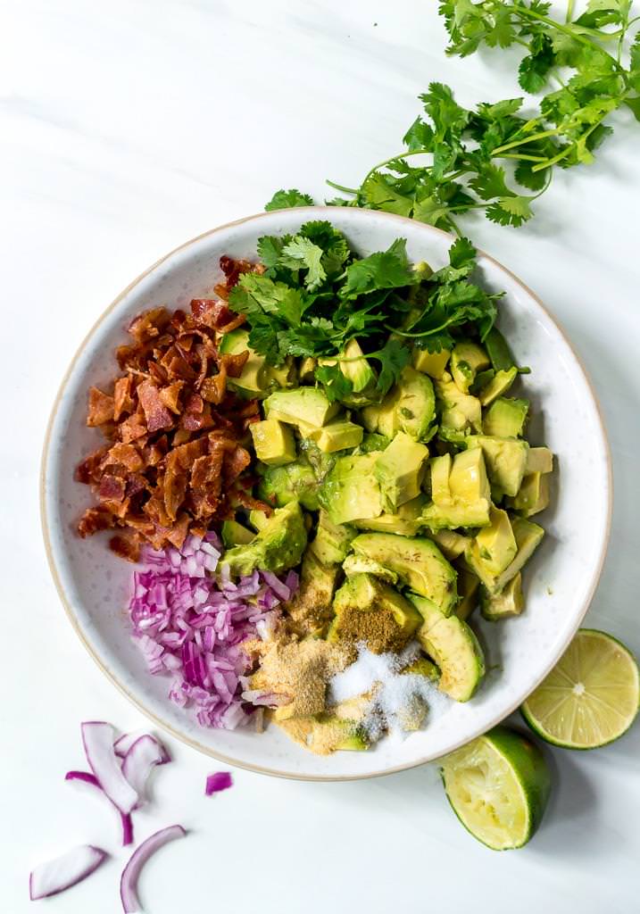 over head photo of bacon guac recipe ingredients in white bowl