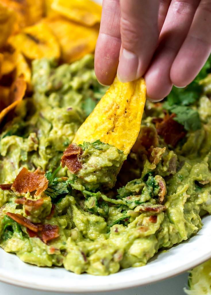 close up photo of plantain chip dipping into bacon guac recipe