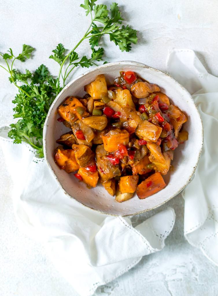 white bowl filled with chipotle chicken vegetable hash, white background with parsley on the side
