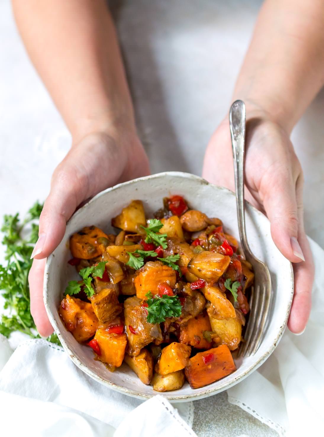 hands holding white bowl with chicken chipotle honey vegetable hash