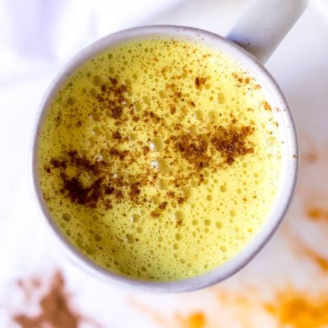 over head photo of golden milk topped with cinnamon in a white mug