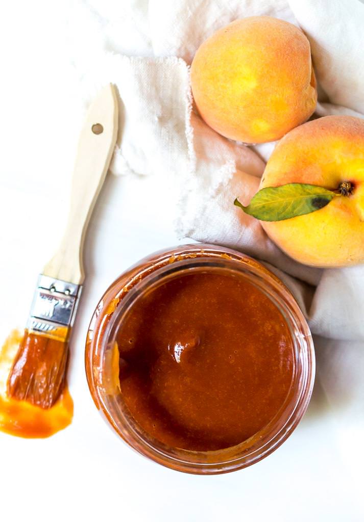 over head photo of peach barbecue sauce recipe with bbq brush and fresh peaches on the side