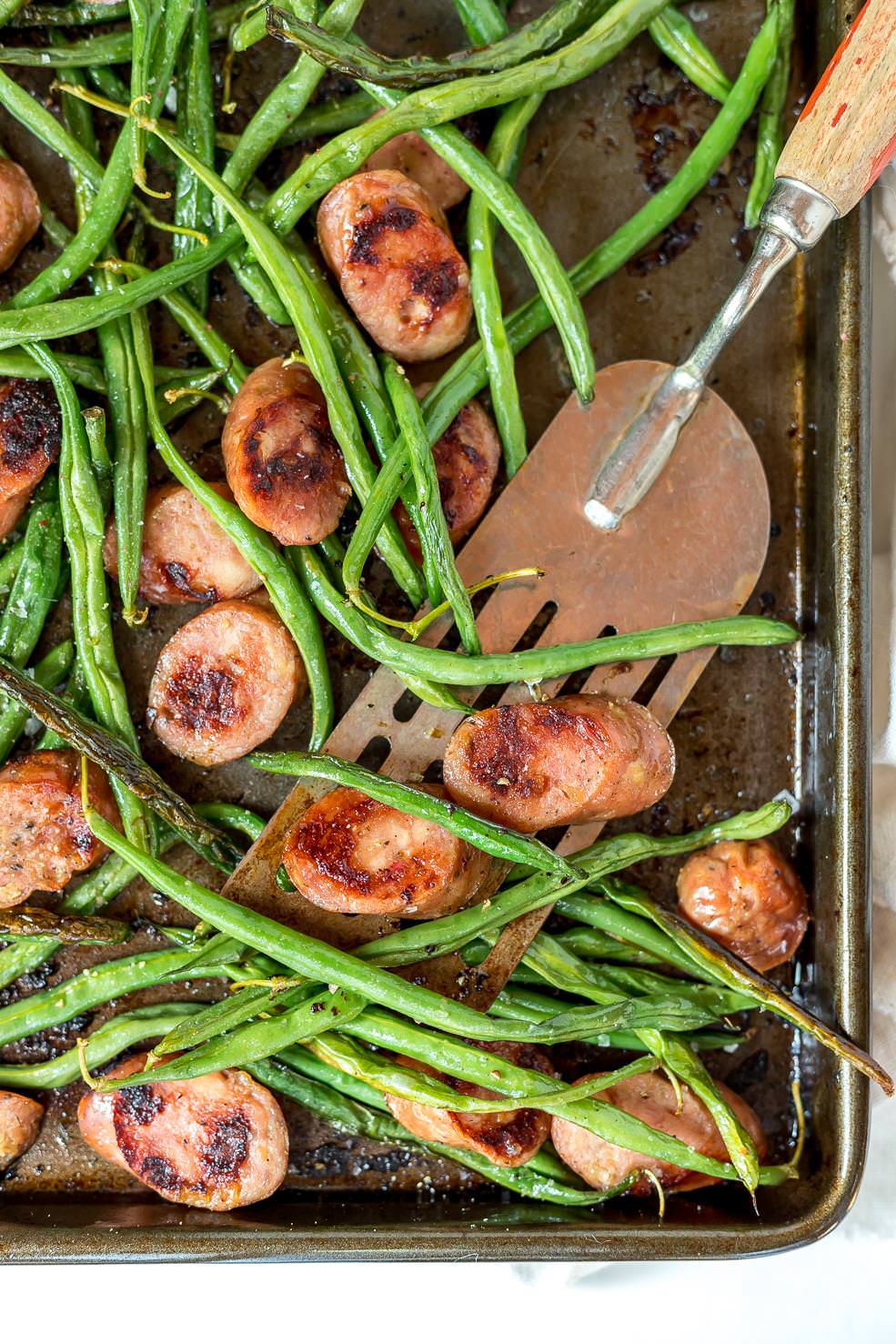 close up of spatula scooping green beans and sausage dinner