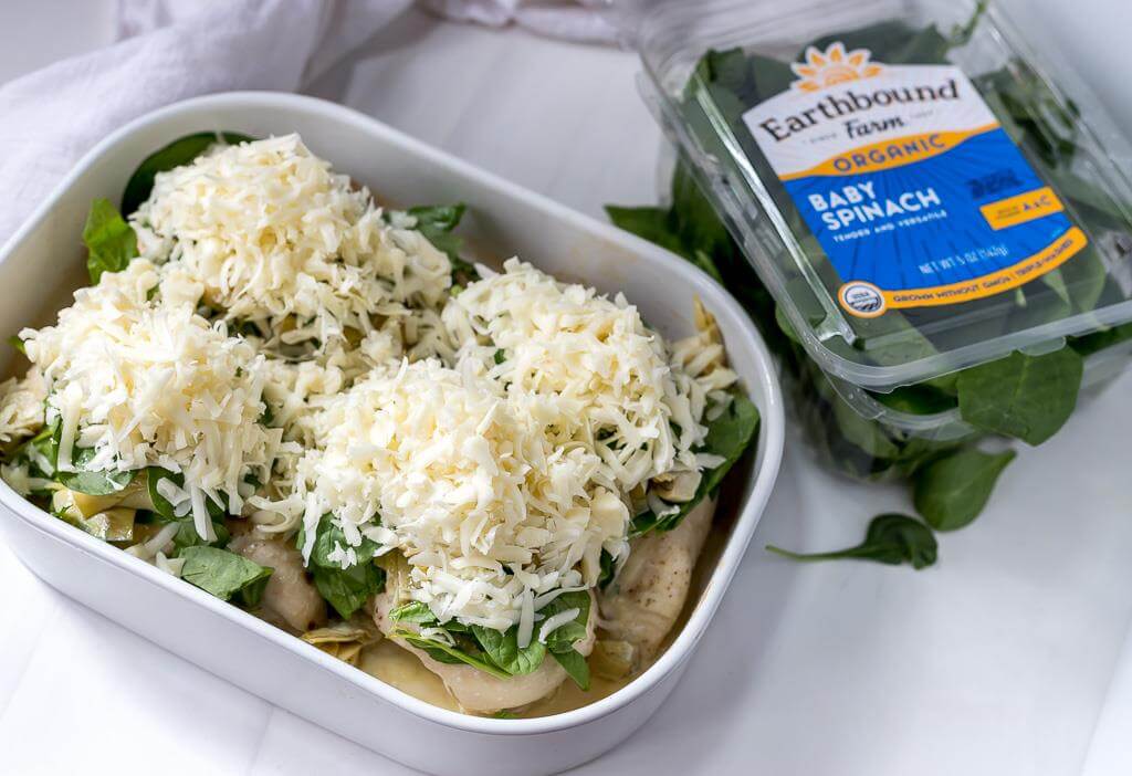 partially baked chicken breast topped with spinach, artichokes and shredded mozzarella cheese