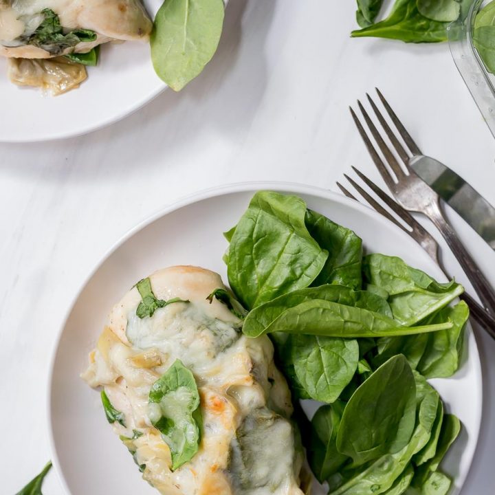 plated smothered chicken with fresh spinach on the side