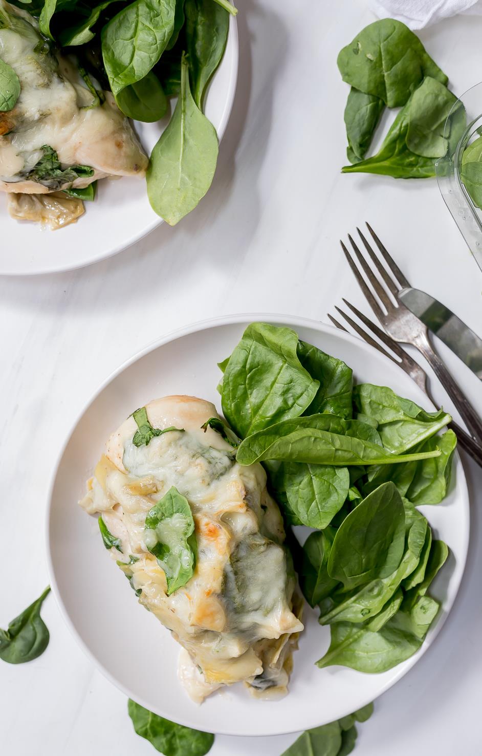 plated smothered chicken with fresh spinach on the side