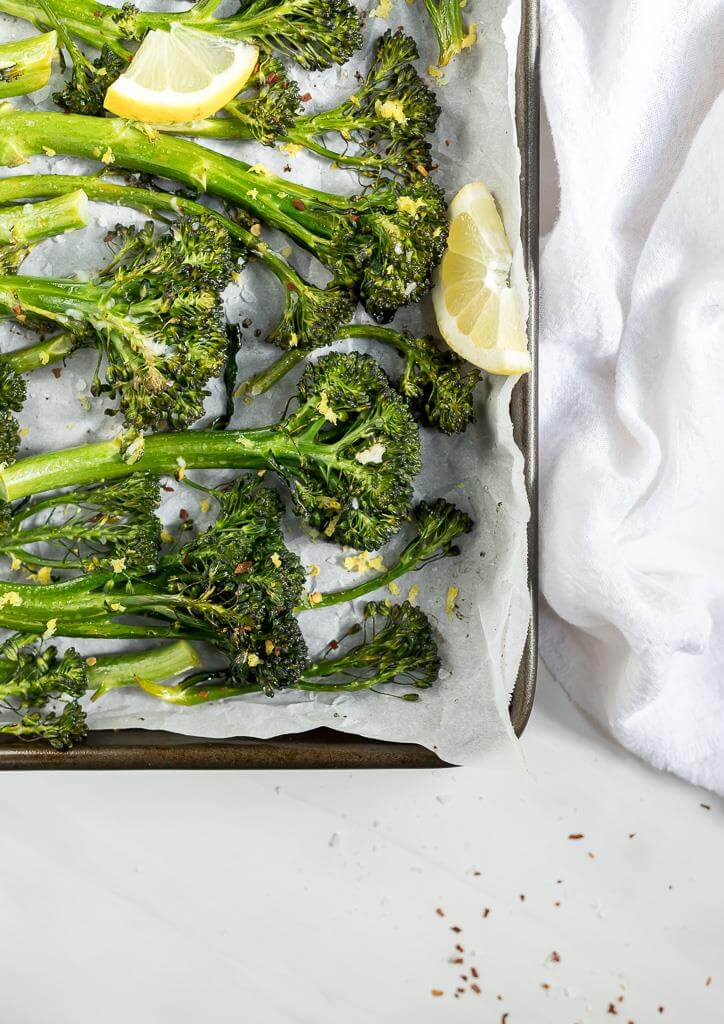 roasted broccolini with lemon wedge on parchment lined pan