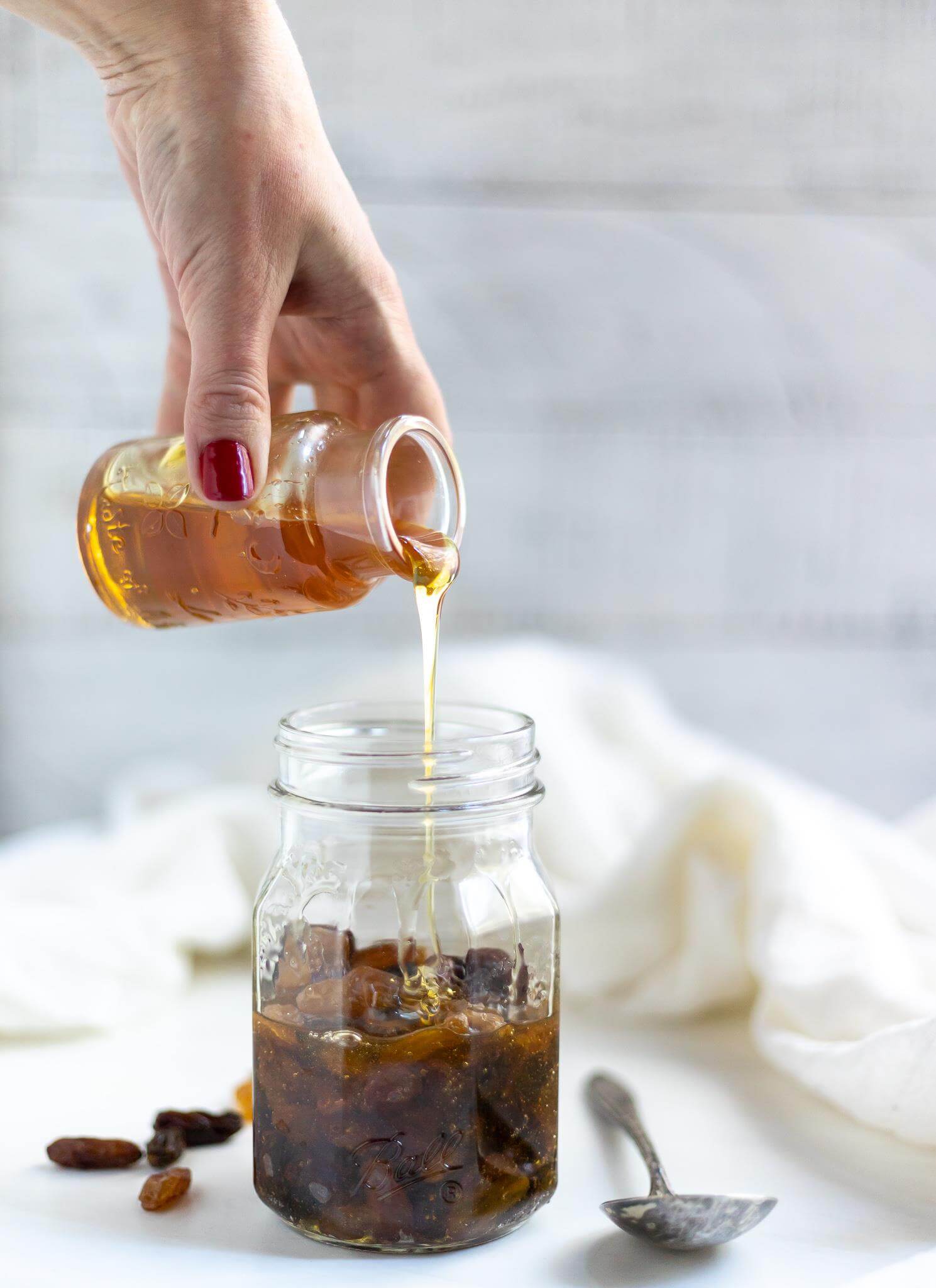 honey being poured over a jar filled with raisins