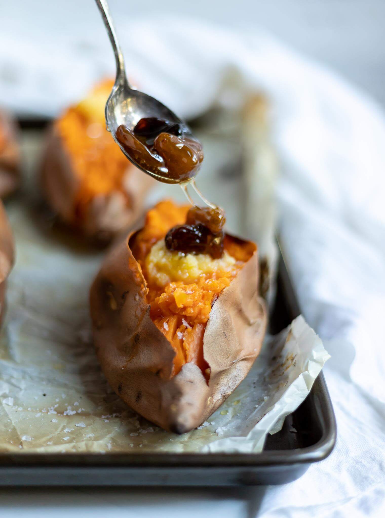 roasted sweet potatoes being topped with honey raisins
