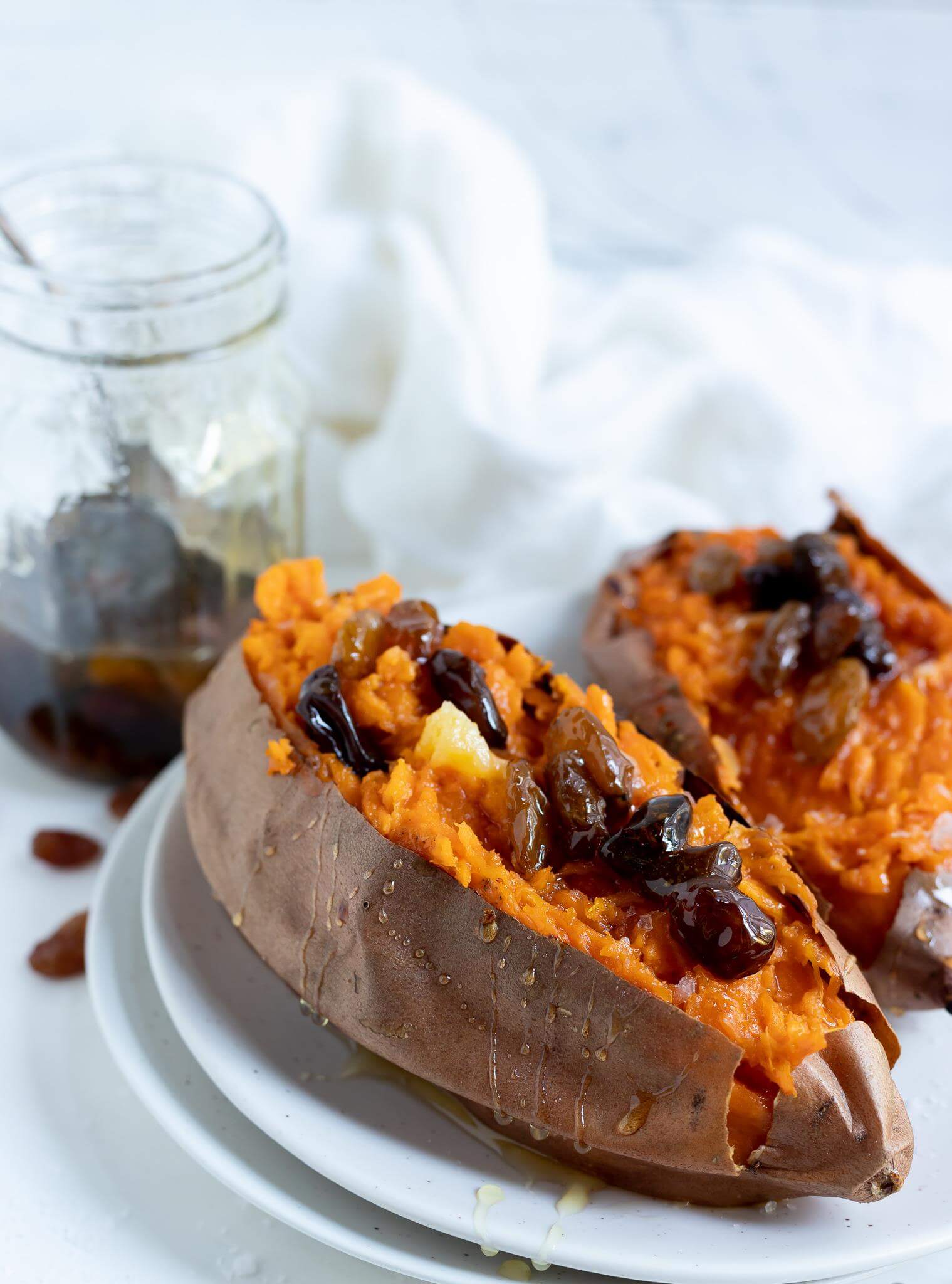 roasted sweet potatoes topped with spiced honey raisins on a white plate