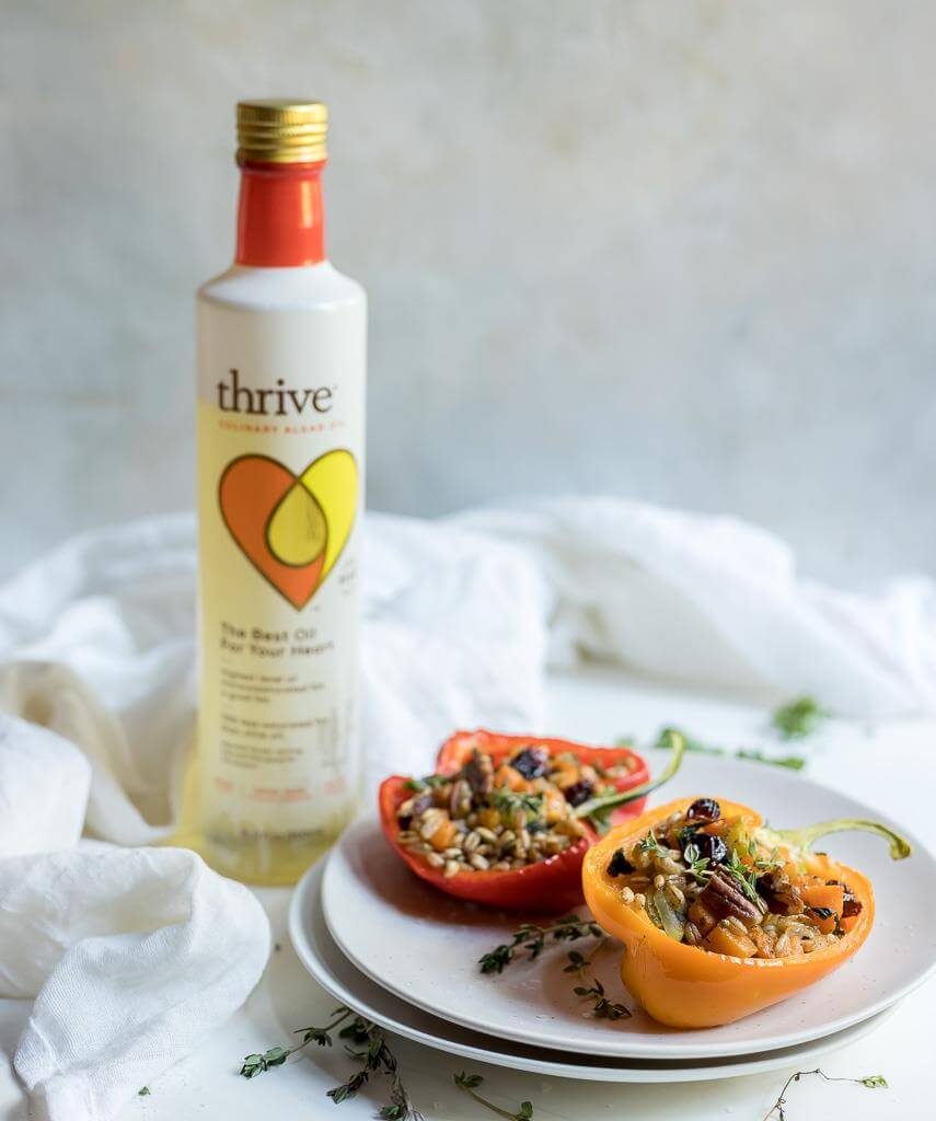 farro salad stuffed peppers on white plate with bottle of Thrive Culinary Algae Oil in background