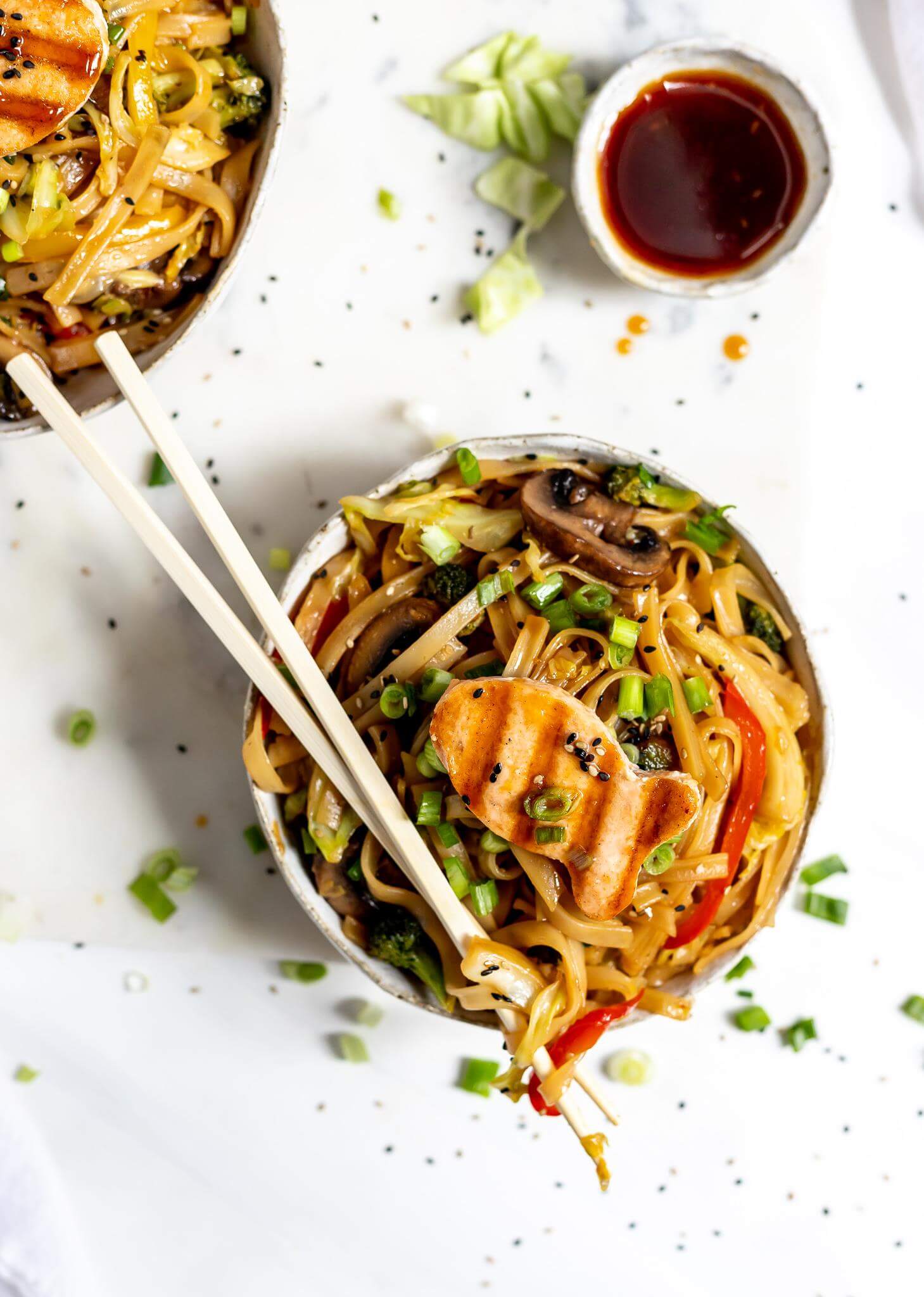 bowl of chines noodles with chopsticks on top and a small bowl of sauce on the side