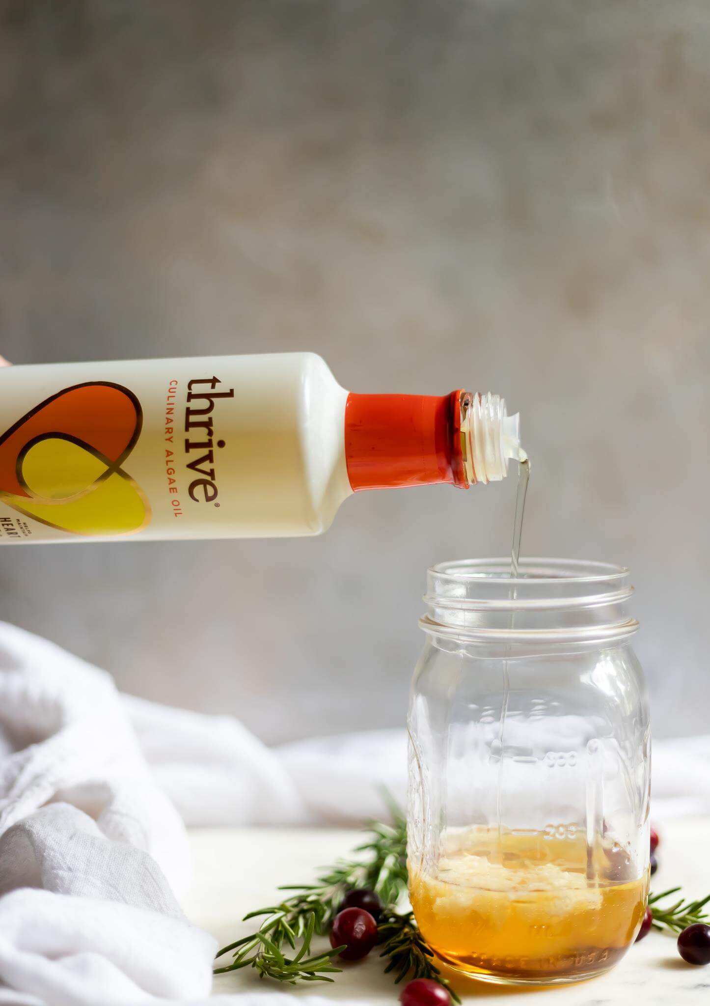 thrive algae oil being poured into a glass jar with rosemary chicken sauce