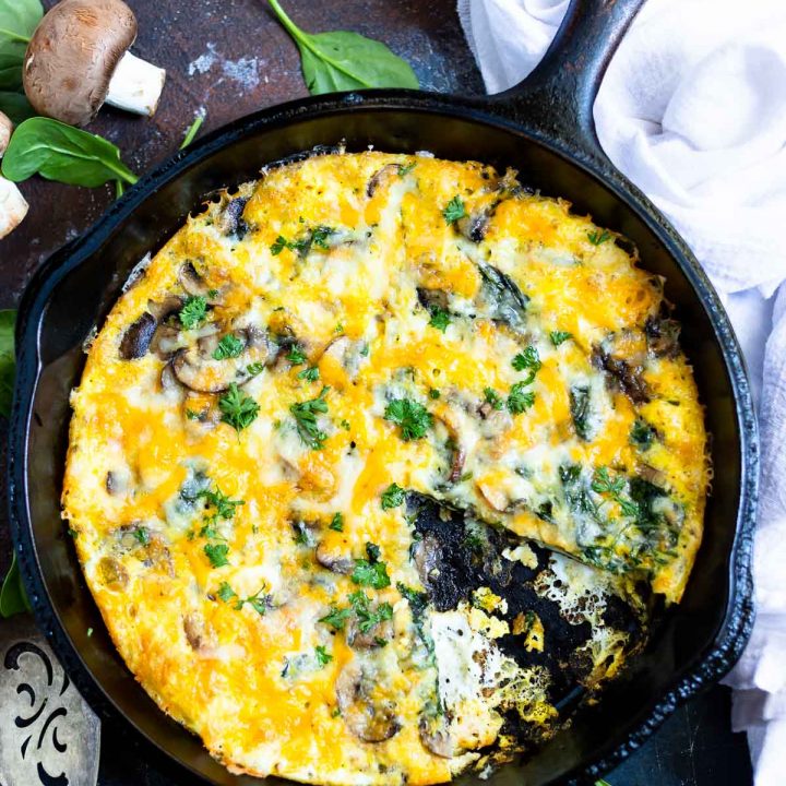 mushroom spinach frittata recipe in black cast iron pan with a slice removed