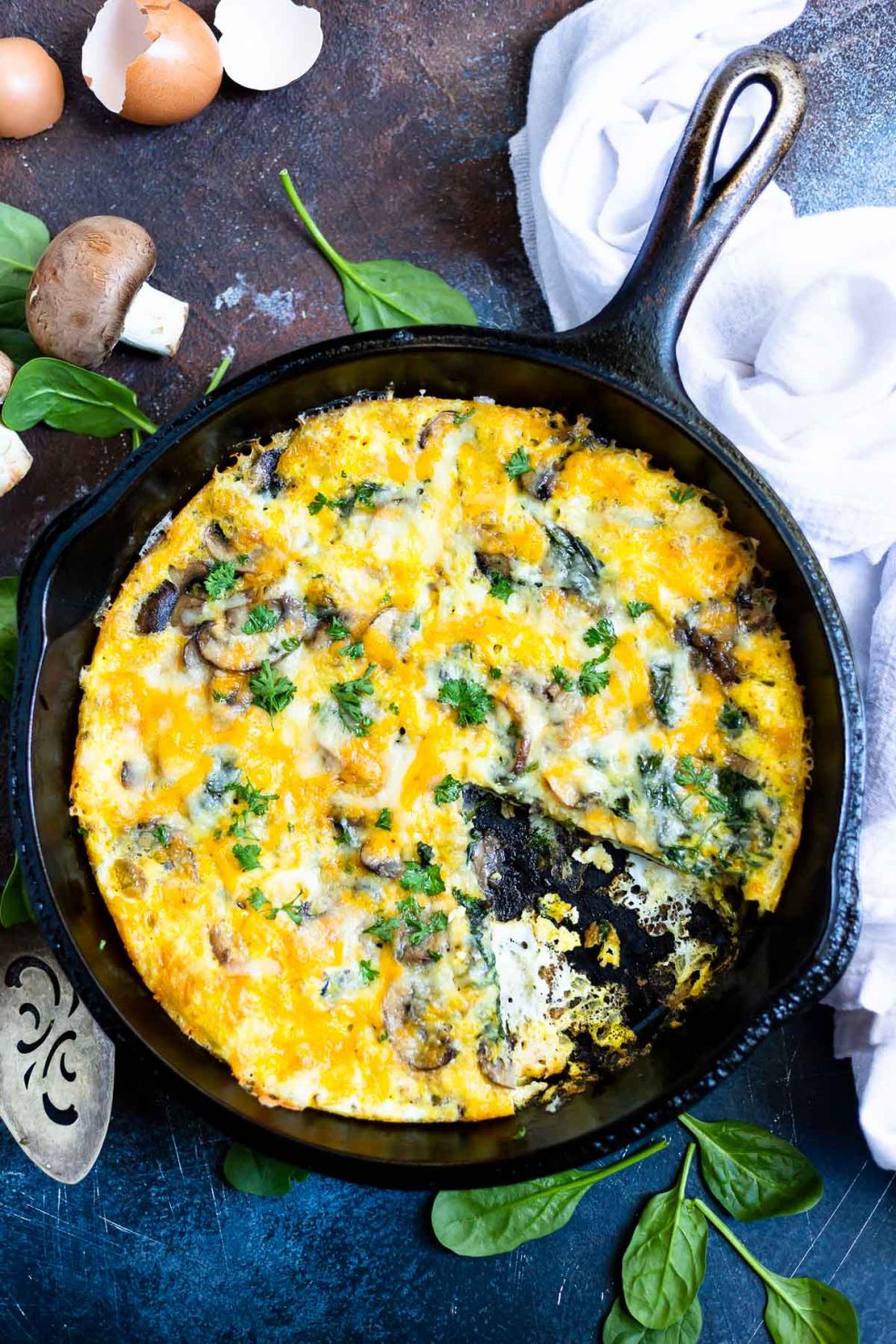 mushroom spinach frittata recipe in black cast iron pan with a slice removed