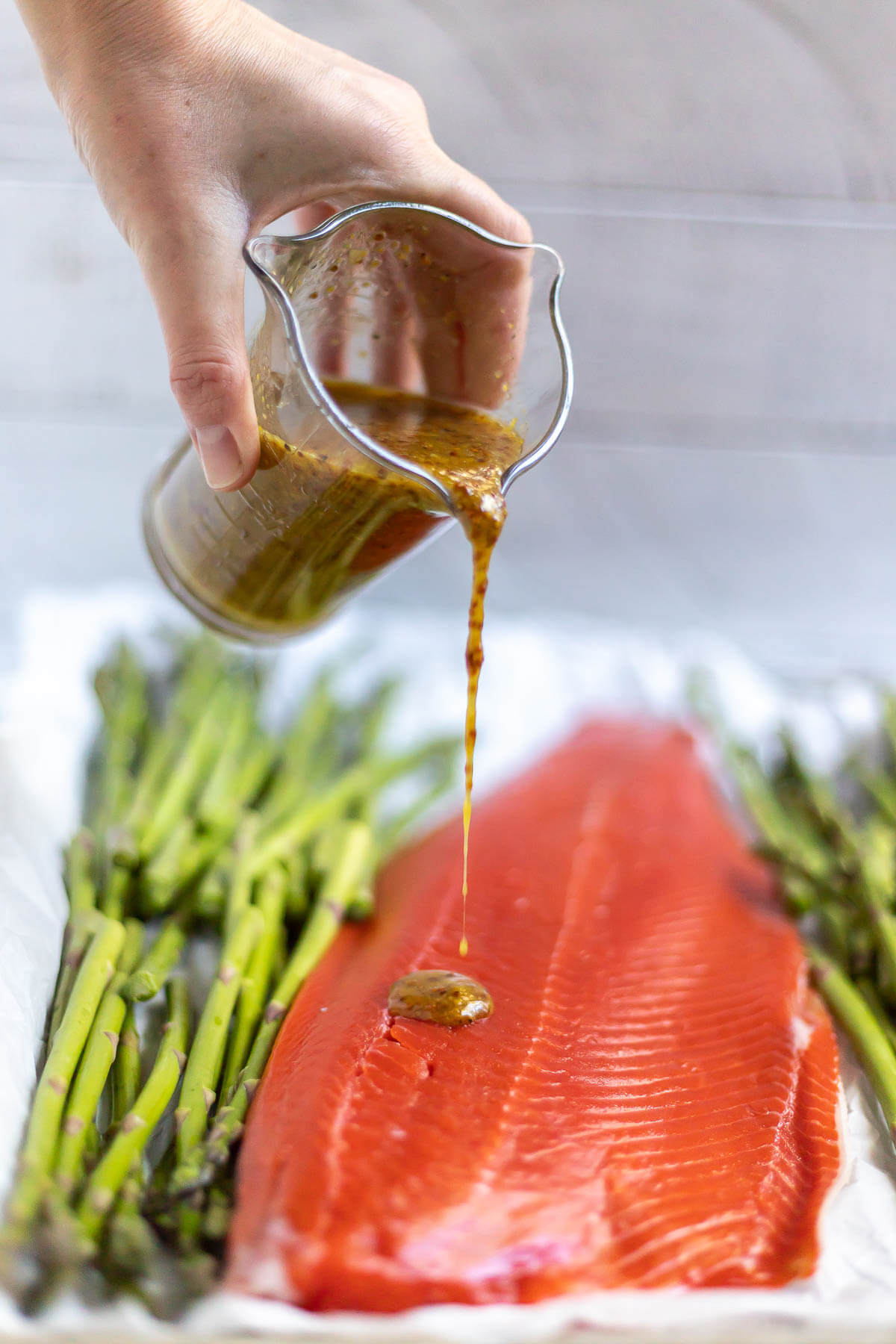 maple mustard sauce being drizzled over salmon and asparagus