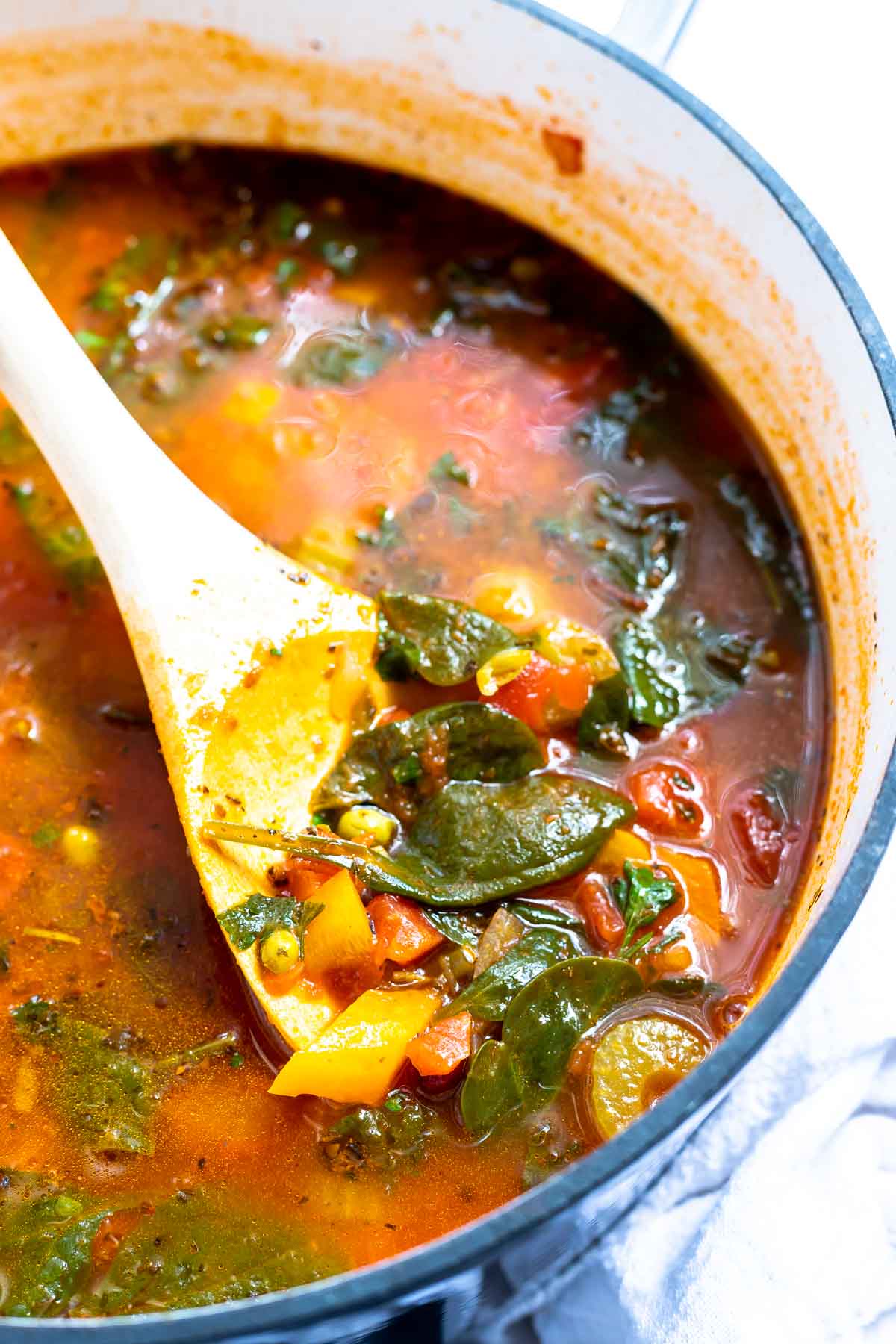 vegetable soup in pot with large wooden spoon