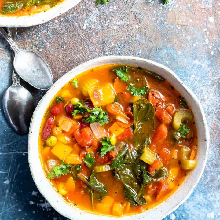 white bowl filled with vegetable soup with spoons on the side