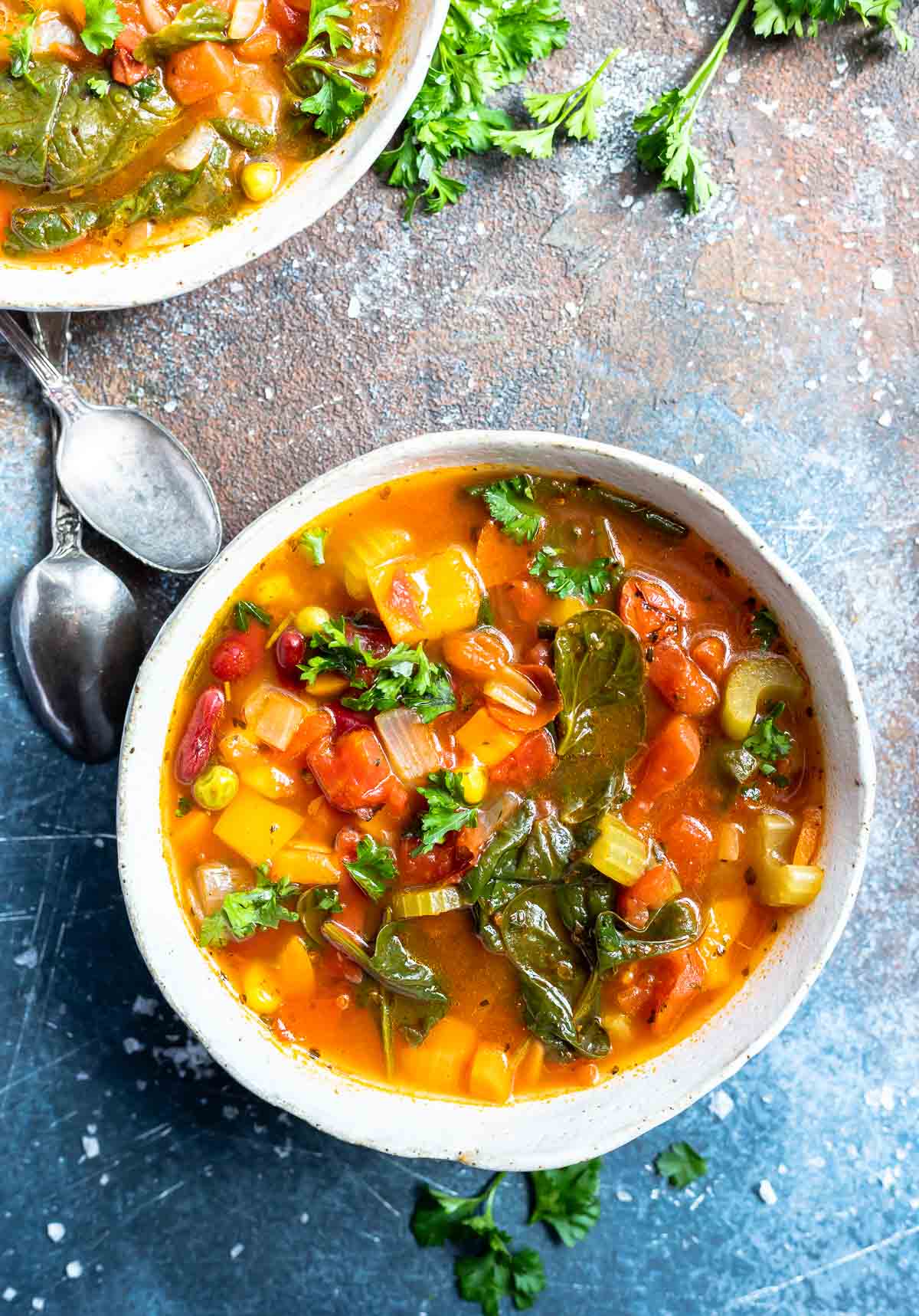 white bowl filled with vegetable soup with spoons on the side
