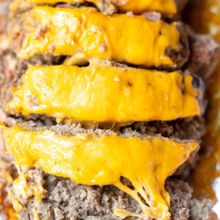 bacon cheeseburger meatloaf topped with orange cheddar cheese and cut into slices to serve