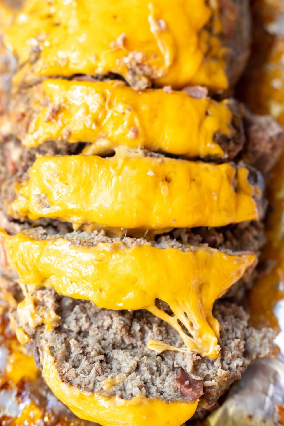 bacon cheeseburger meatloaf topped with orange cheddar cheese and cut into slices to serve