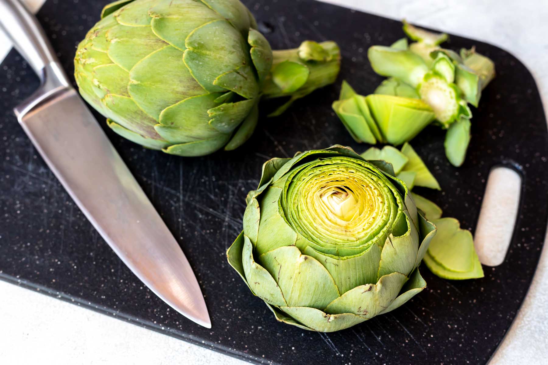 artichoke on cutting board getting prepared for pressure cooker
