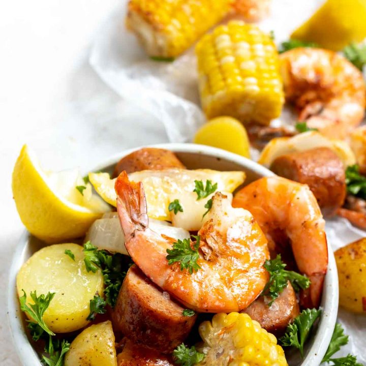 sheet pan shrimp boil shrimp, corn, potatoes, sausage and lemons in a white dish