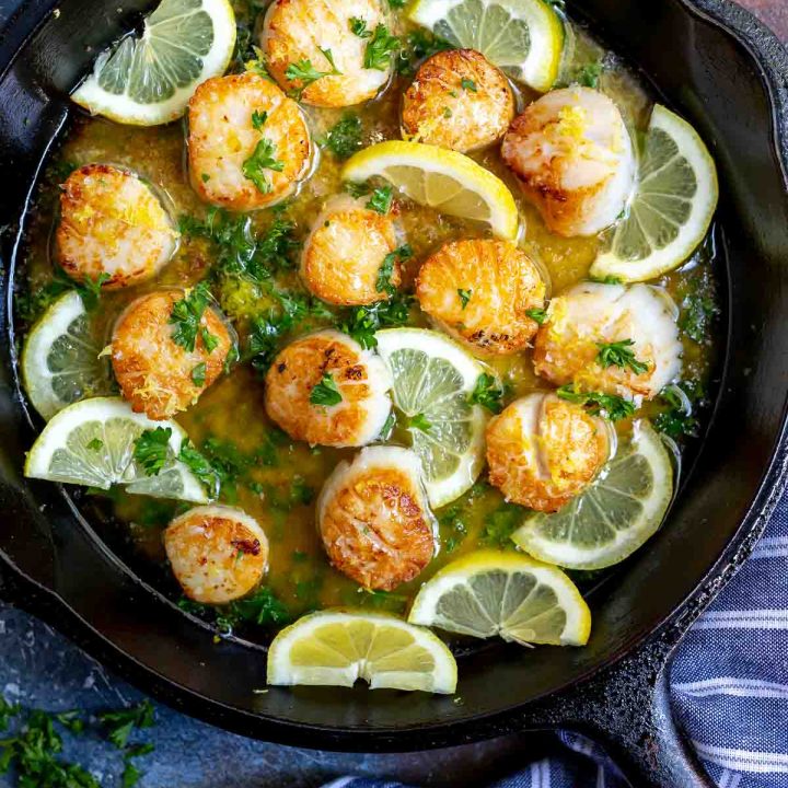 seared scallops with lemon slices in cast iron pan