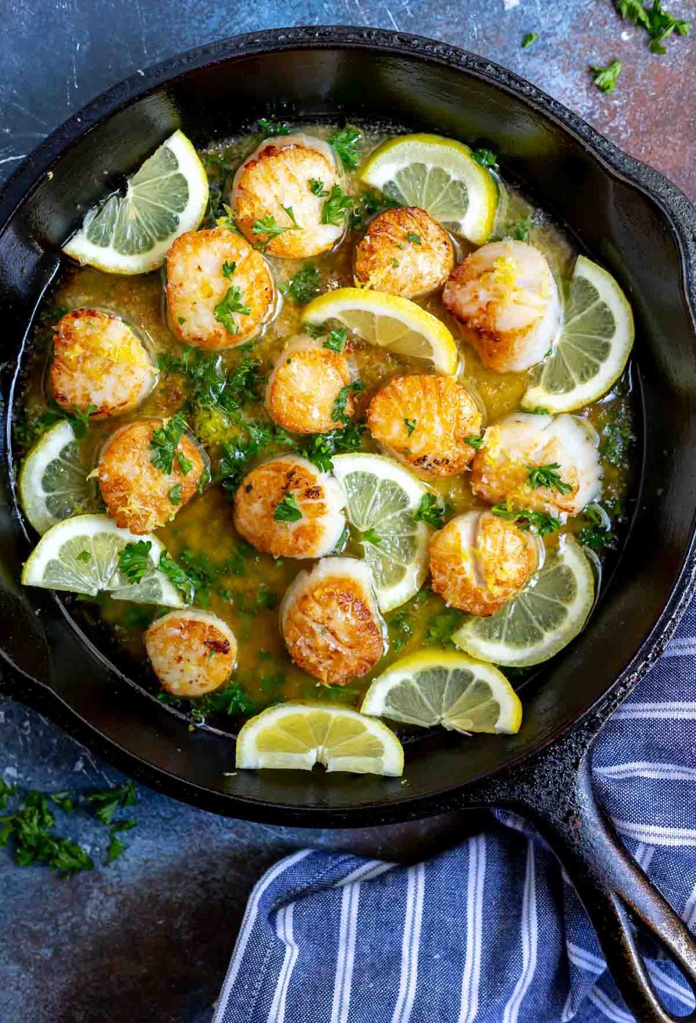 seared scallops with lemon slices in cast iron pan