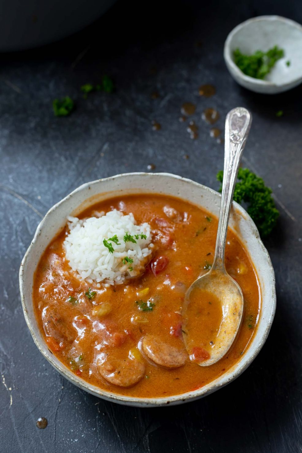 chicken and sausage gumbo in white bowl with spoon