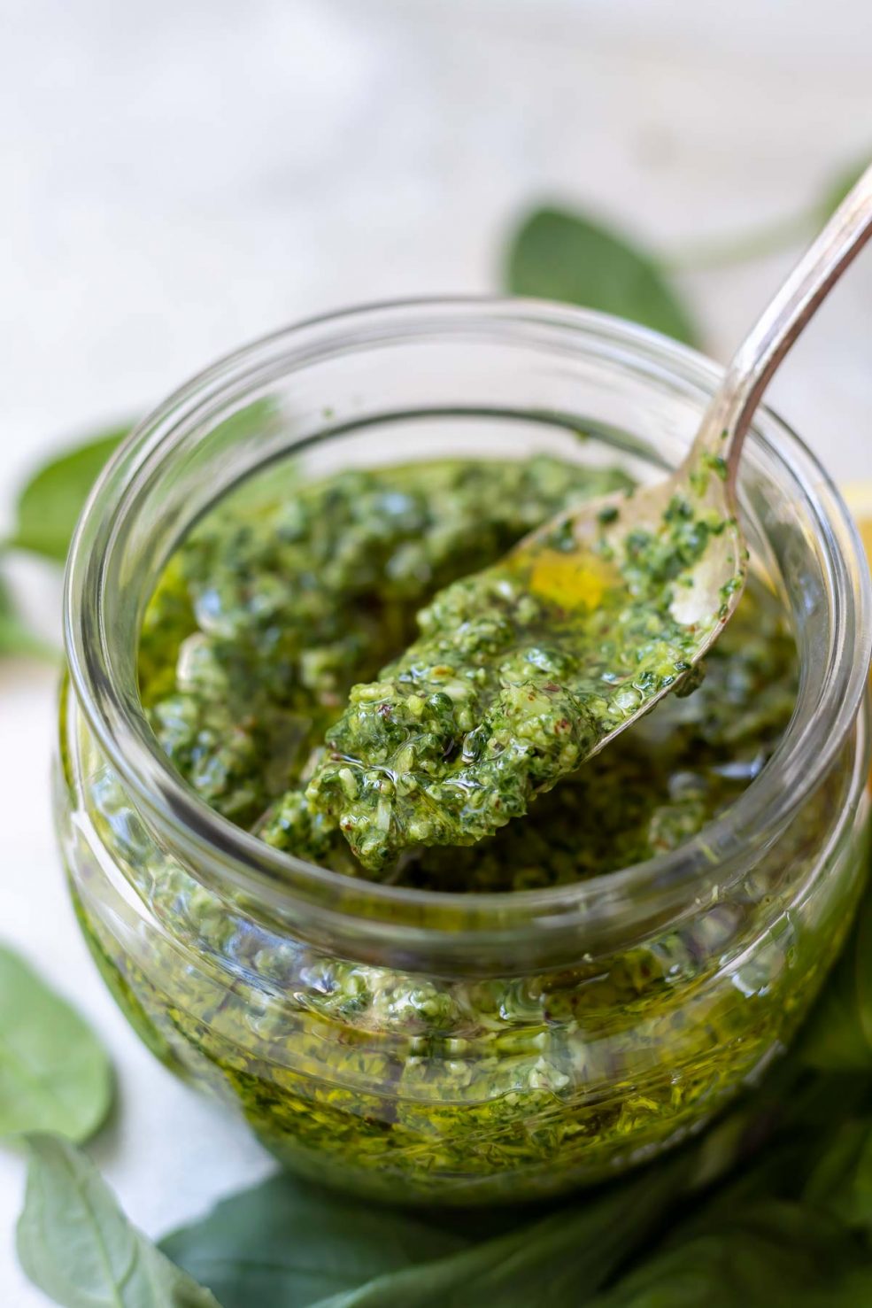basil spinach pesto in glass jar with silver spoon