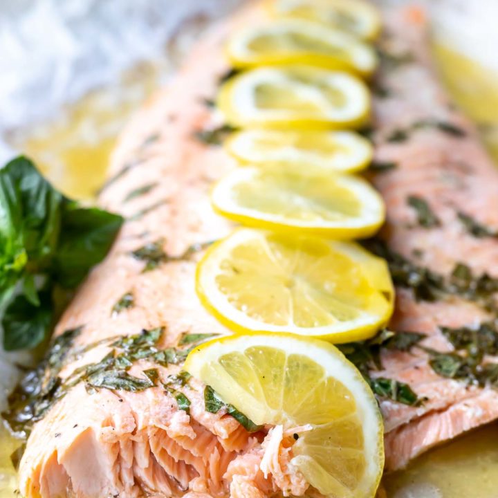 baked salmon topped with fresh chopped basil and sliced lemons