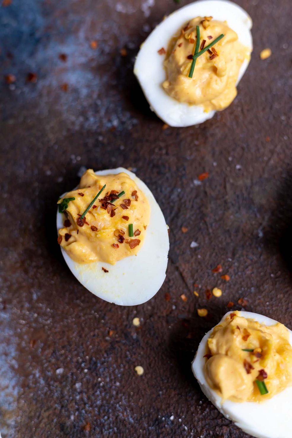 deviled eggs topped with chili flakes and chives