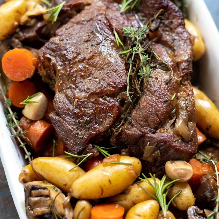 pot roast, potatoes, carrots and mushrooms ready to be served