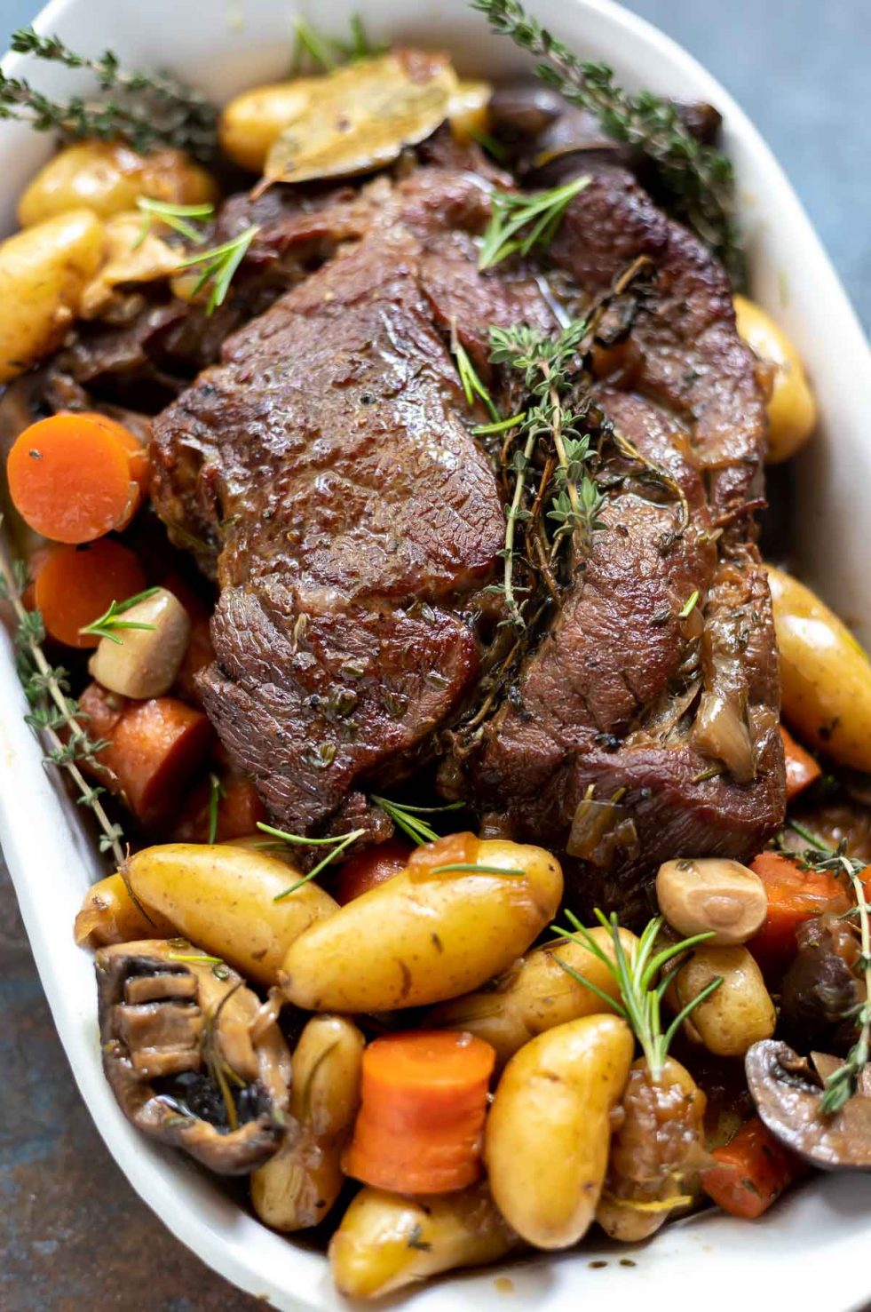 pot roast, potatoes, carrots and mushrooms ready to be served