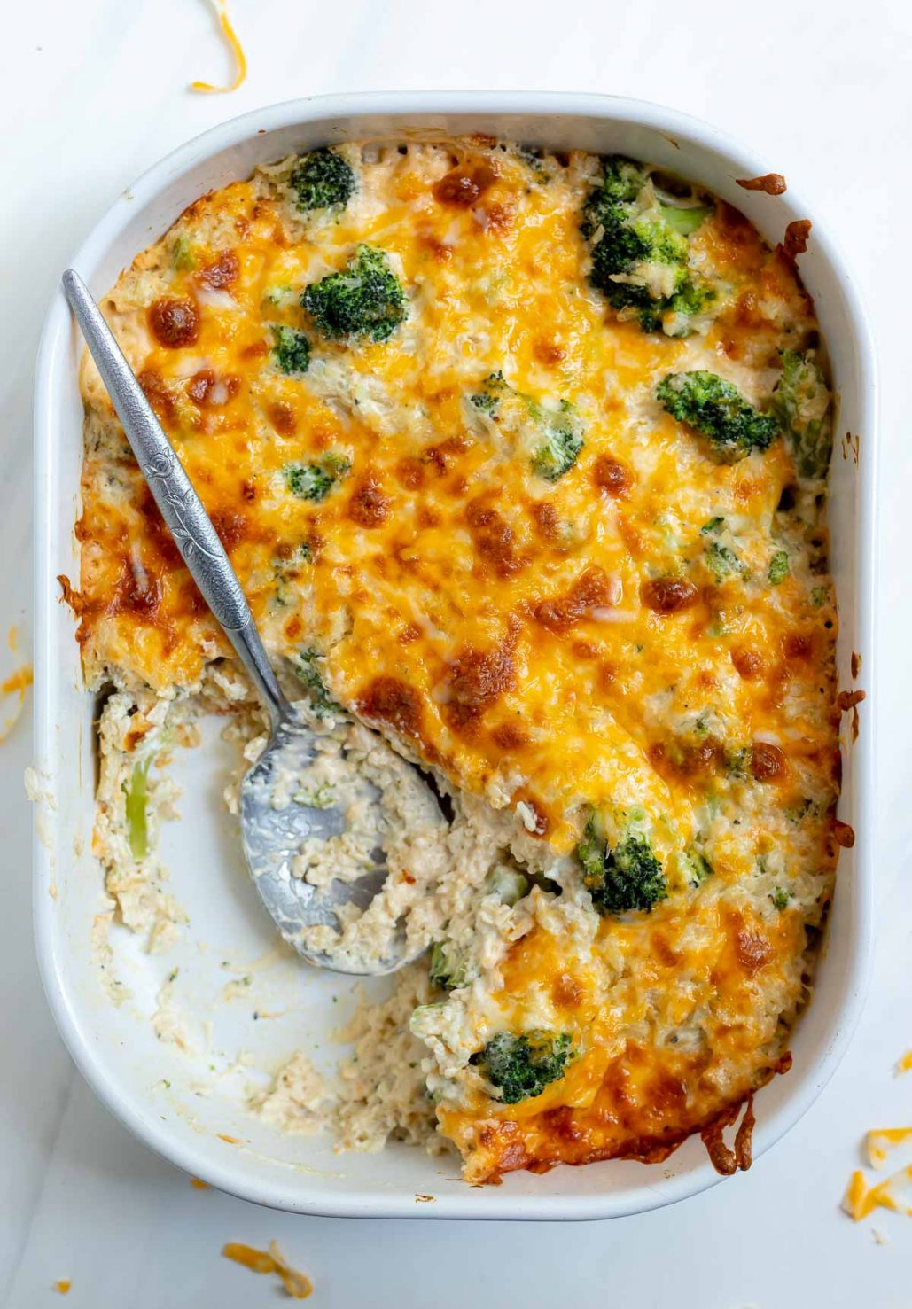 broccoli casserole in white dish with silver serving spoon