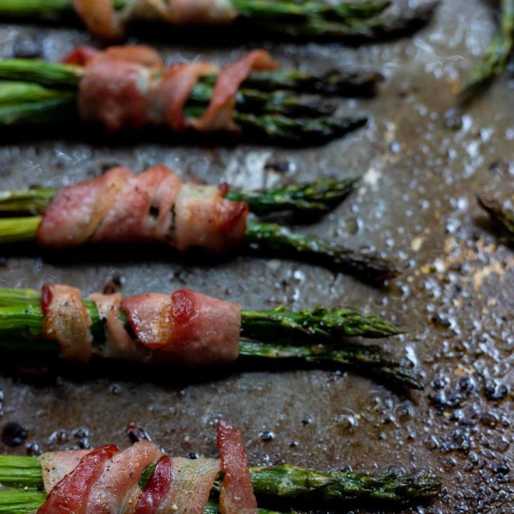 asparagus wrapped in bacon on rimmed baking sheet