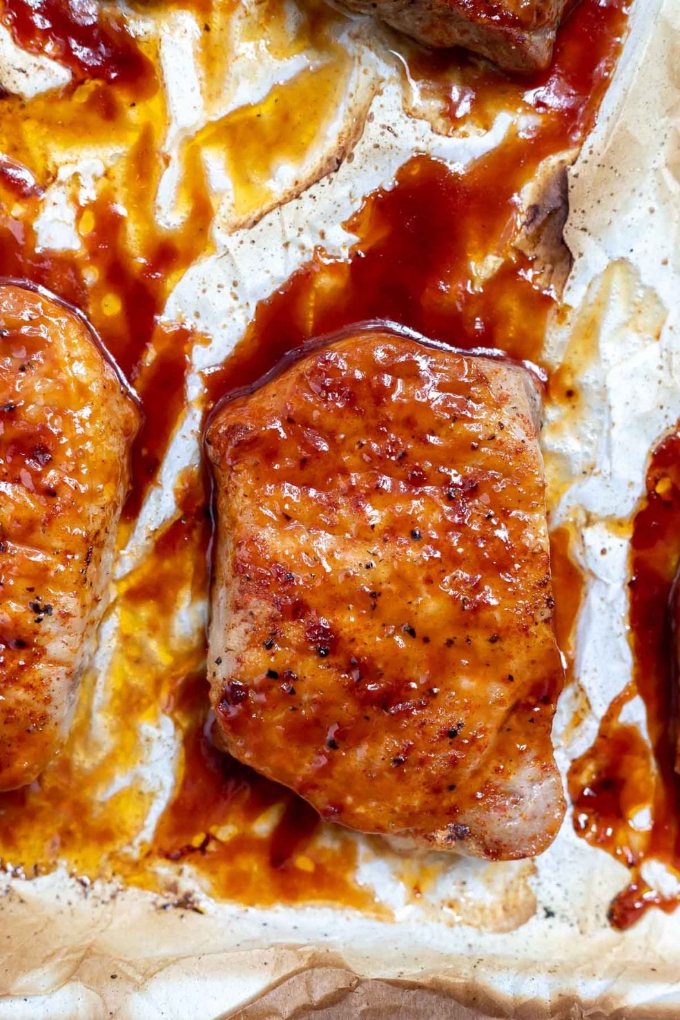 baked pork chop slathered with bbq sauce on parchment paper