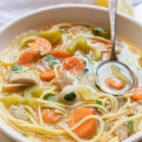 chicken noodle soup in white bowl with spoon