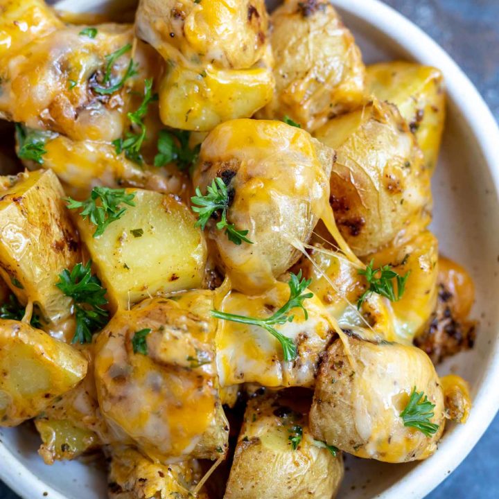 potatoes topped with melted cheese and parsley in white dish