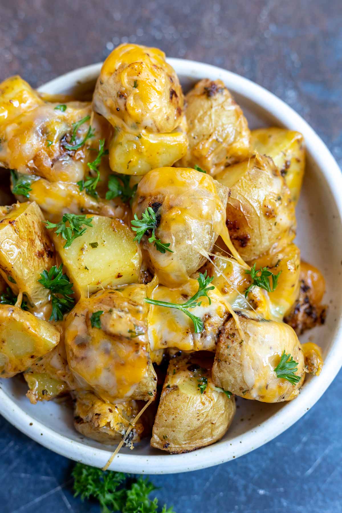 potatoes topped with melted cheese and parsley in white dish