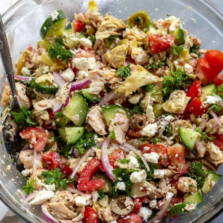 tuna salad ingredients mixed together in clear glass bowl