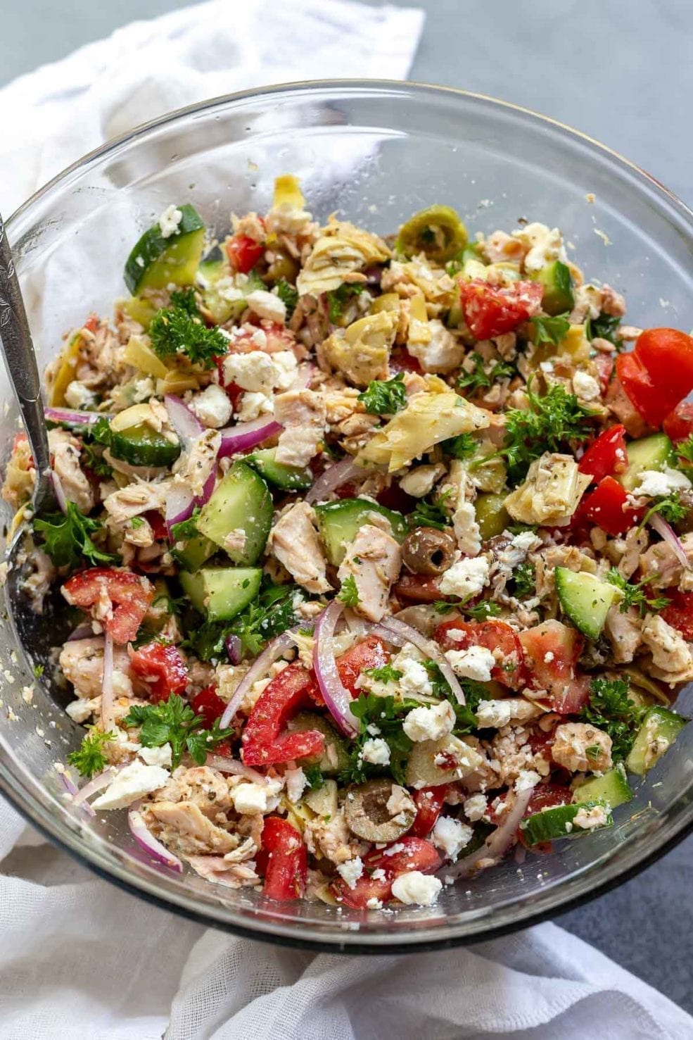 tuna salad ingredients mixed together in clear glass bowl