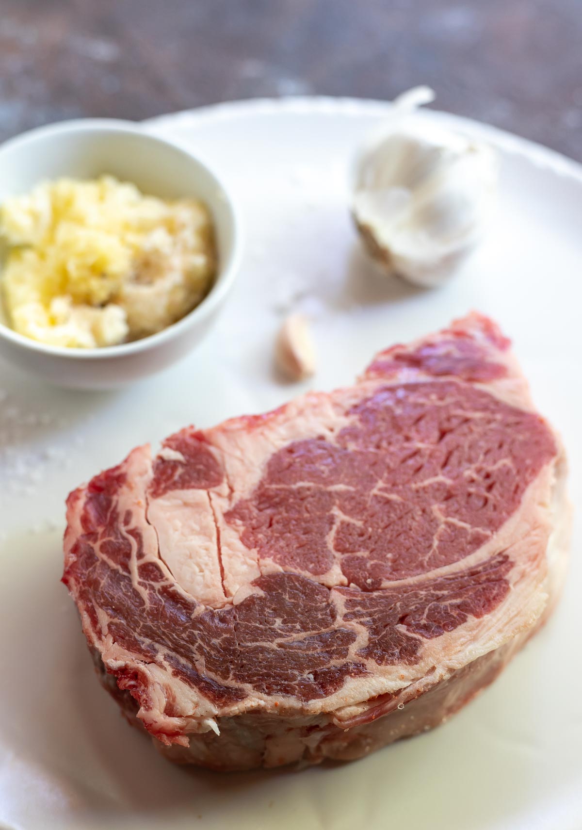 raw steak and grated garlic on cutting board